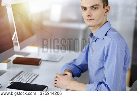 Young Successful Businessman Works With Computer, Sitting At The Desk In A Sunny Modern Office. Head