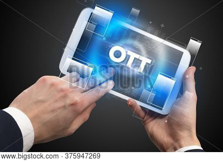 Close-up of a hand holding tablet with OTT abbreviation, modern technology concept