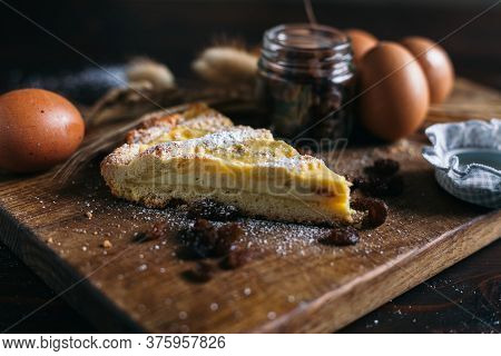Traditional Italian Cake With Ricotta Cheese And Raisin, Eggs, Jar And Powdered Sugar On Wooden Back