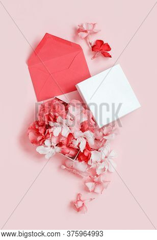 Red Envelope And Gift Box Full Of Flowers  Over A Pink Background Top View