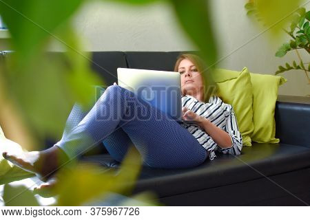 Woman Lying On A Sofa In The Home Garden With A Laptop Working