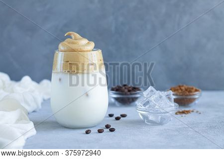 Glass Of Tasty Dalgon Coffee Drink With Coffee Beans And Ice Cubes On Stone Table. Copy Space