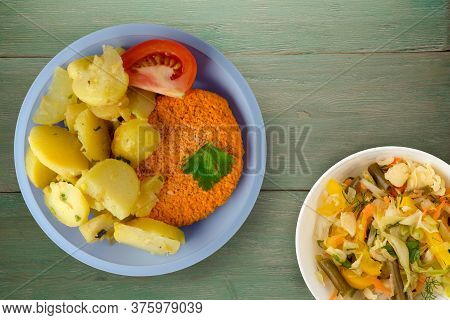 Meatball With Potatoes On Green Wooden Background. Meatball With A Slice Of Tomato On Light Blue Pla