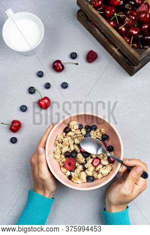 Girl Eating Breakfast And Muesli With Spoon In A Bowl With Seasonal Fruits
