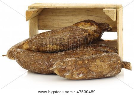 mazzo di radici di manioca in una cassa di legno su sfondo bianco
