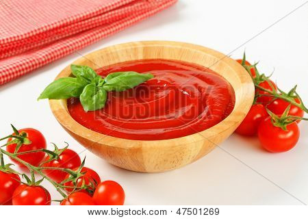 ketchup in una ciotola di legno con pomodori freschi e biancheria modello quadrato
