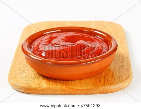 Schüssel Ketchup-Sauce in einer Schüssel auf ein hölzernes Schneidebrett