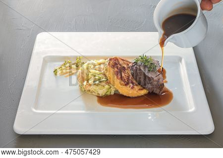 Pouring Sauce On A Dish From Roast Venison, Flat Bread Dumpling And Round Shaped Cabbage Vegetable O