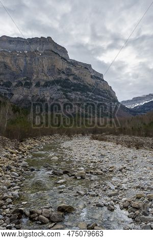 A Mountain River Flows Through A Valley Between Large Rocky Mountains, Arazas River, Ordesa Y Monte 