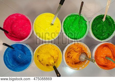 Top View, Colorful Fabric Printing Inks In White Buckets.
Stirring The Ink For Multicolored Tee Shir