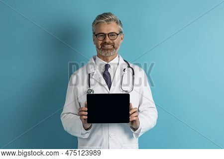 Cheerful Middle Aged Doctor Showing Digital Tablet With Blank Screen
