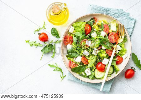 Spring Salad In Craft Plate. Spinach, Arugula, Tomatoes And Feta With Olive Oil. Top View On White.