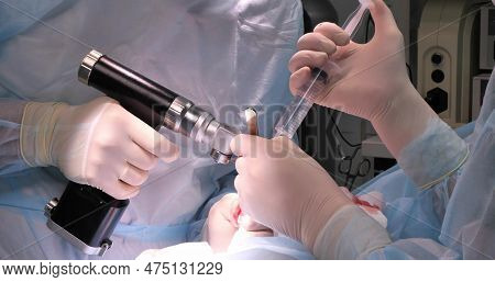 A Veterinary Surgeon Cuts Down A Drilled Section Of A Broken Bone In A Pet In The Operating Room. Fo