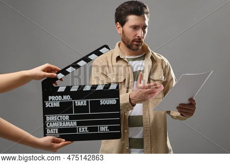 Actor Performing While Second Assistant Camera Holding Clapperboard On Grey Background