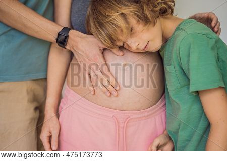 Mothers Day, Fathers Day, Little Cute Blond Boy Touching Moms Pregnant Belly, Husband Holding His Wi