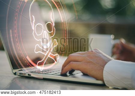 Close Up Of Male Hand Using Laptop On Desktop With Coffee Cup And Digital Red Skull On Blurry Backgr