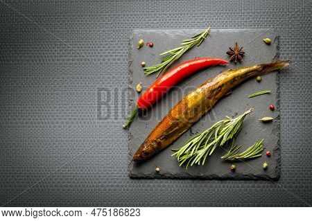 Delicious Smoked Fish On A Serving Board With Rosemary And Pepper Served For Lunch. Dark Space For A