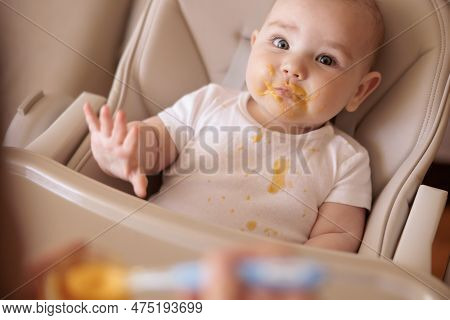 High Angle View Of Mother Feeding Cheerful Baby Boy With Porridge, Baby Sitting In High Chair All Me