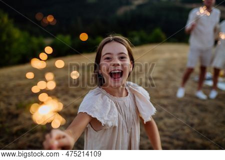 Portrait Of Excited Girl With Sparkler During Family Picnic In The Nature.