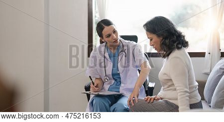 Doctor Woman Holding Knee And Looking At Aged Woman Patient While Explaining. Support For Strained M