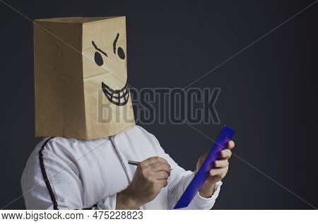An Angry Man In A White Shirt With A Bag On His Head, With A Drawn Angry Smiley Face, Holds A Tablet
