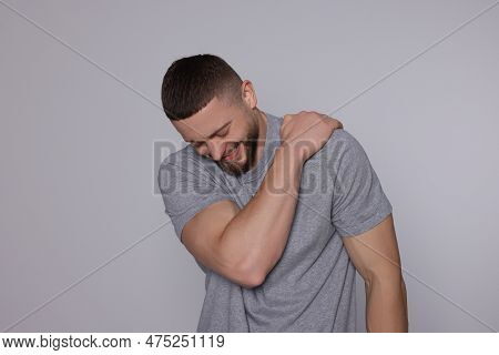 Man Suffering From Pain In His Shoulder On Light Grey Background. Arthritis Symptom