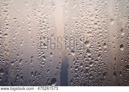 Backlit Chaotic Water Drops On Lightbeige And Blue Glass Background. Condensation After Rain Or Show