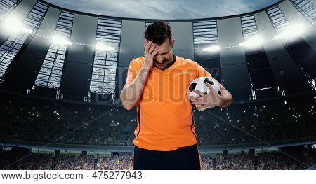 Loosing Game. Man, Professional Football Player In Orange Uniform Holding Head With Hands In Despair