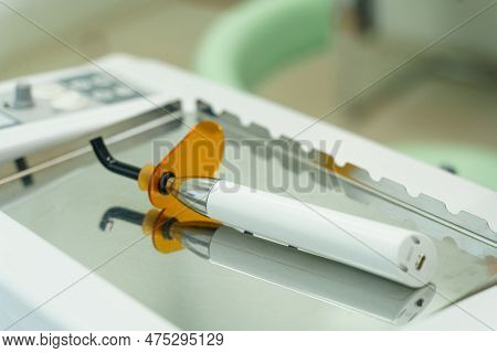 On The Mirror Surface Lies A Device For Filling And Drying Teeth - A Dental Polymerization Lamp.