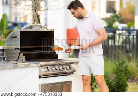 Man Cooking Meat On Barbecue In The Backyard Of The House. Handsome Man Preparing Barbecue. Barbecue