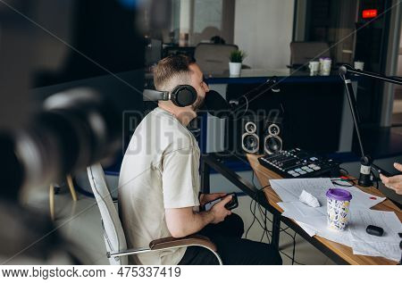 Portrait Of Young Male Radio Host Having A Drink, Looking Focused While Speaking In Microphone, Mode