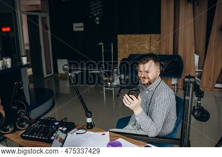 Portrait Of Young Male Radio Host Having A Drink, Looking Focused While Speaking In Microphone, Mode
