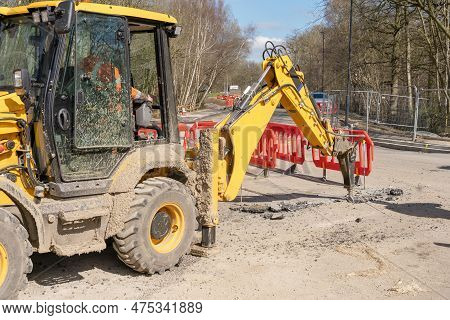 Excavator With Hydraulic Jack Hammer  Breaking Asphalt In Preparation For Drainage Works Close Up An