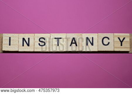 Word Instancy From Small Gray Wooden Letters Lies On A Purple Background