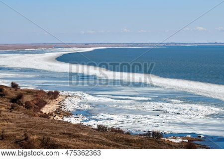 February Seashore With Melting Ice Near Shore, Seasonally Nature Landscape Of Coming Spring. Russian