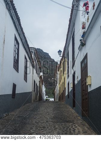 Narrow Cobbled Street With Traditional White Houses In The Village Of Agulo Located In Green Valley 