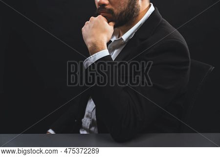 Businessman Or Lawyer Wearing Formal Black Suit Sitting At Table On Isolated Black Background. Conce