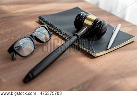 Closeup Top View Black Wooden Gavel Hammer With Book And Glasses On Wooden Office Desk Background As