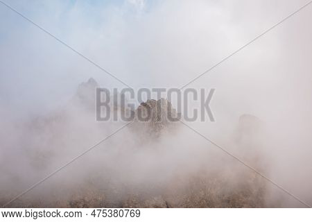 Scenic Alpine Landscape With Rocky Mountains In Dense Low Clouds In Morning Sunlight. Colorful Mount