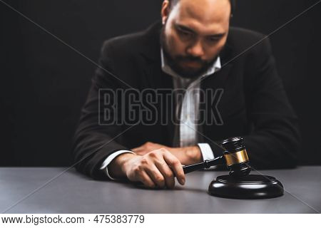 Focus Wooden Gavel Hammer With Burred Lawyer In Black Suit Holding Gavel In Background On His Desk, 