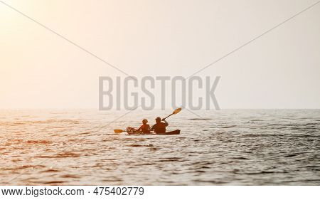 Happy Couple Kayaks In An Inflatable Kayak On The Sea At Sunset. Couple Kanoeing In The Sea Near The