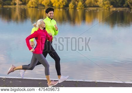 Jogging Concepts. Running Couple While Training Outdoors On Road At River For Durable Marathon Prett