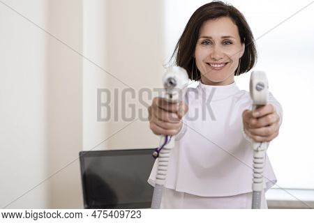 Positive Laughing Female Doctor Posing In Doctor's Smock While Holding Two Intence Pulse Light Appar