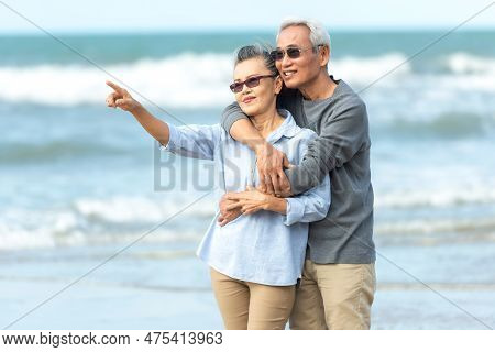 Asian Lifestyle Senior Couple Walking Chill And Pointing On The Beach Happy In Love Romantic And Rel