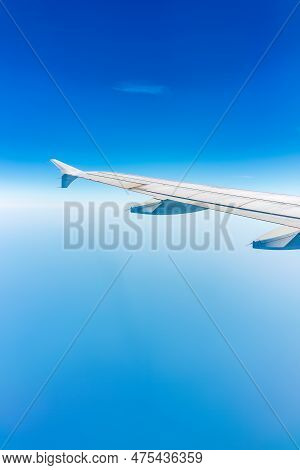 View From The Airplane Window At A Beautiful Cloudy Sky And The Airplane Wing. Earth And Sky As Seen