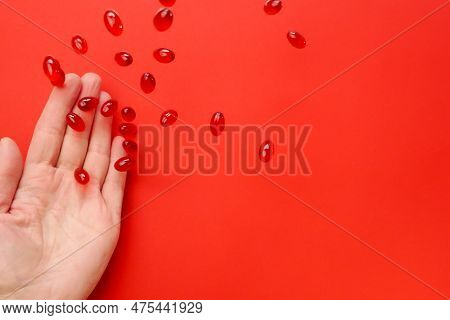 Krill Oil .omega Fatty Acids.flying Gelatin Red Krill Oil Capsules In A Womans Hand On A Red Backgro