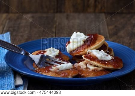 A Fork Cutting Into A Messy Plateful Of Pikelets/pancakes/battercakes To Illustrate An Overindulgent