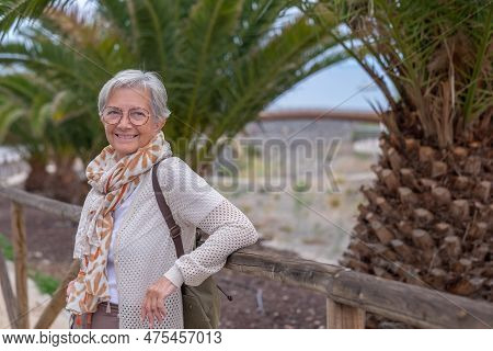 Portrait Of Senior Gray Haired Woman With Backpack In Public Park Enjoying Retirement, Healthy Lifes