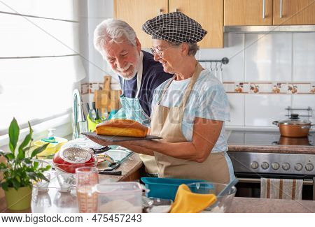 Senior Caucasian Woman In The Home Kitchen Proudly Displays A Freshly Baked Homemade Plumcake To Her