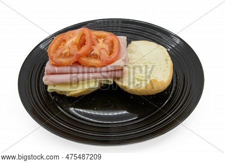 Side view of ham and cheese sandwhich with boiled ham, alpine lace swiss cheese, tomato, on a roll.